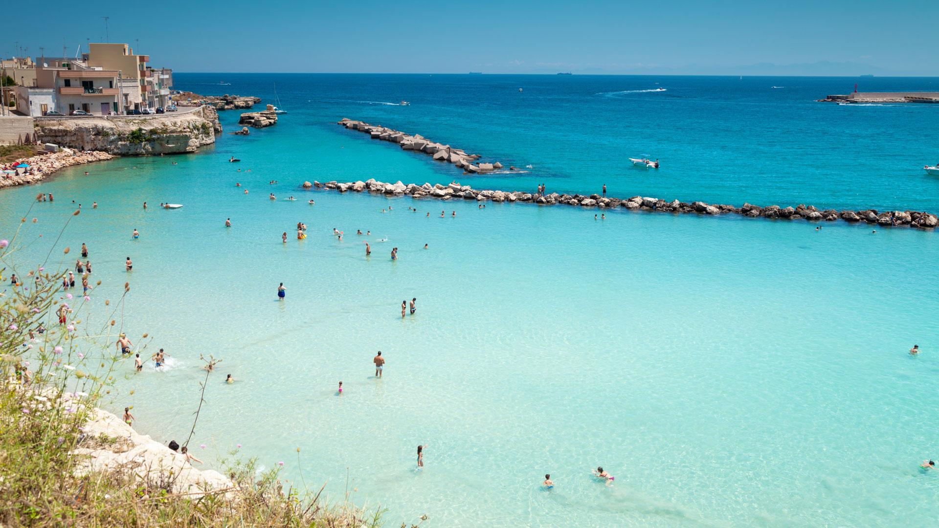Spiaggia affollata, mare turchese, sole splendente; estate italiana vibrante e gioiosa.